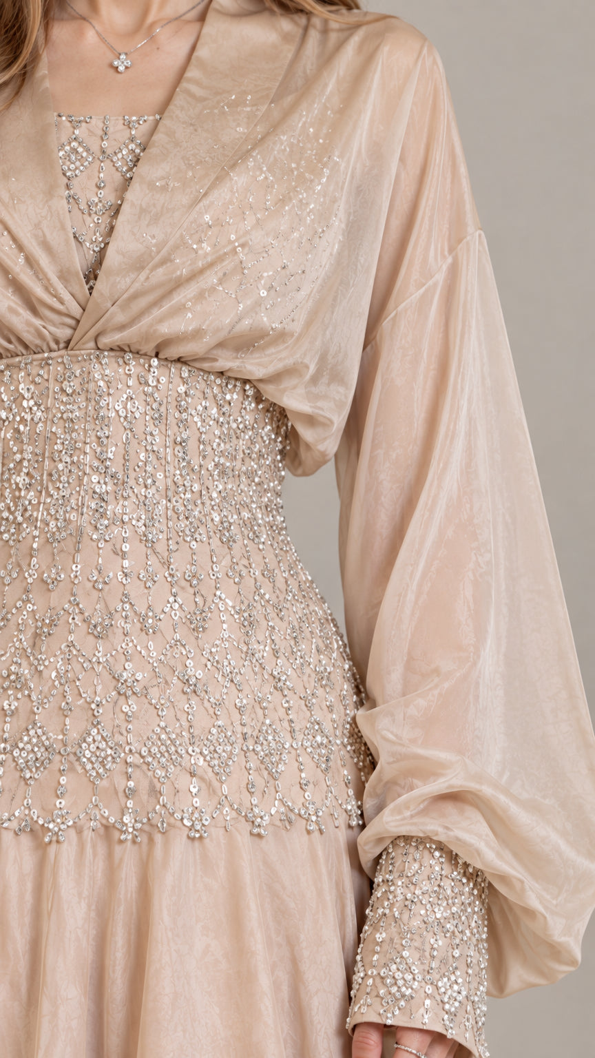 Close-up detail of champagne dress showing intricate beadwork on waist and cuffs
